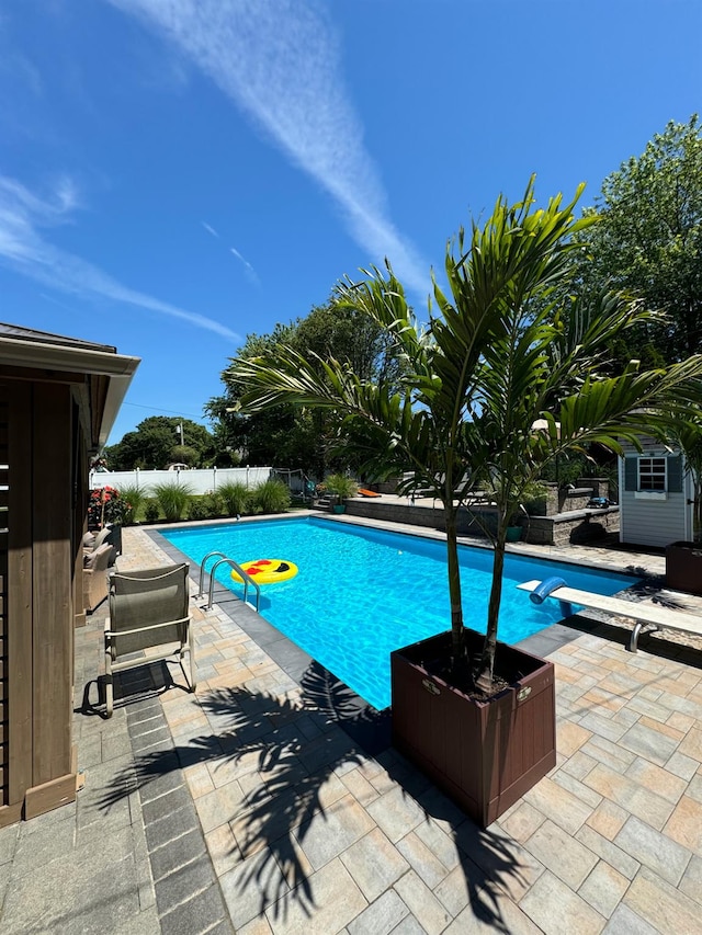 view of pool featuring a fenced backyard, a fenced in pool, a diving board, and a patio
