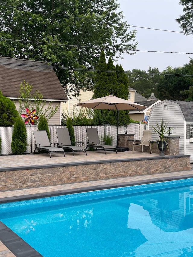 pool featuring fence, a patio, and an outdoor structure