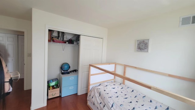 bedroom with visible vents, dark wood finished floors, and a closet