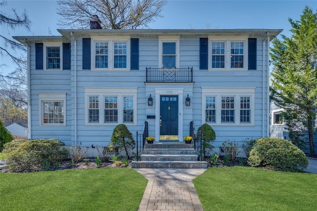 colonial inspired home with a chimney and a front yard