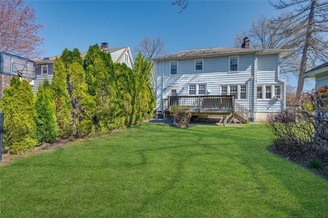 back of property featuring a lawn, a wooden deck, and a chimney