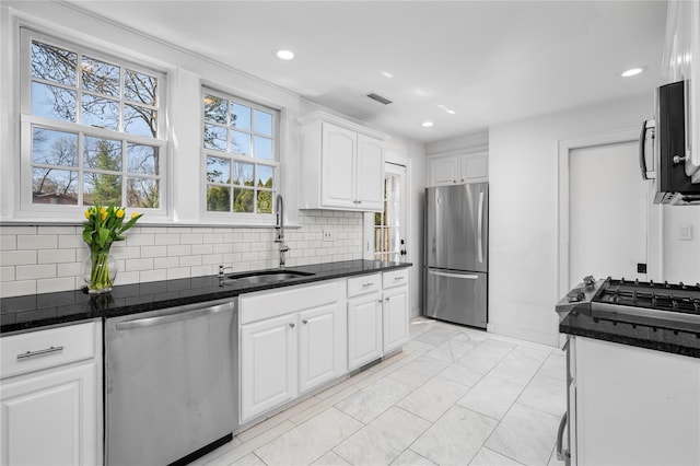 kitchen with a sink, white cabinetry, appliances with stainless steel finishes, and tasteful backsplash