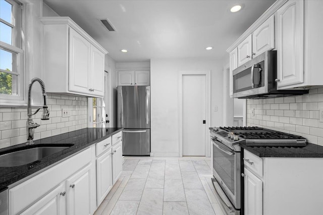 kitchen with a sink, appliances with stainless steel finishes, white cabinets, and visible vents