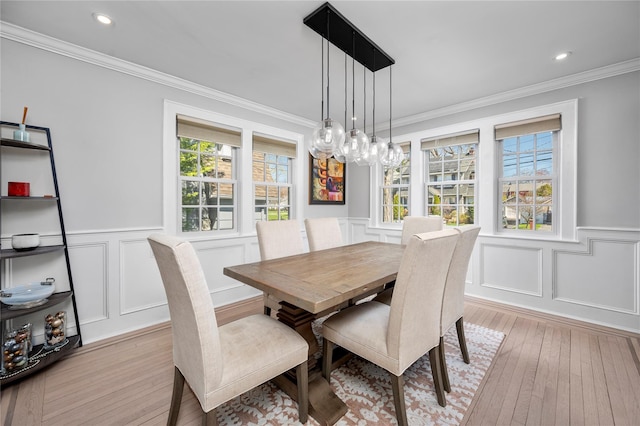 dining area with light wood-type flooring, a decorative wall, and a wainscoted wall
