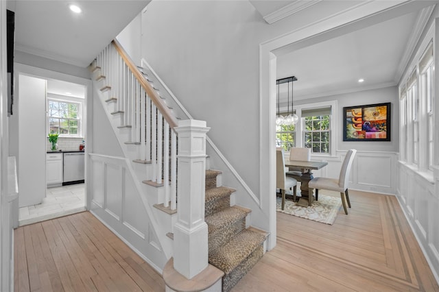 stairs featuring ornamental molding, a decorative wall, recessed lighting, a wainscoted wall, and hardwood / wood-style flooring