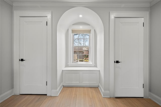 interior space featuring baseboards, ornamental molding, and light wood-style flooring