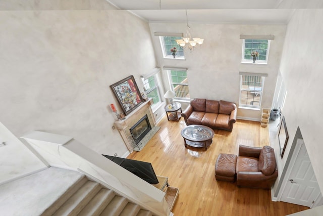 36 Alexander Dr, Washingtonville, NY 10992 - living room featuring a towering ceiling, wood finished floors, a chandelier, a glass covered fireplace, and crown molding