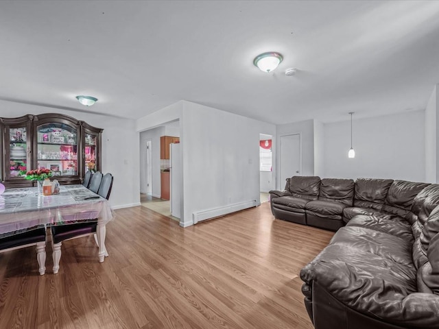 living area with baseboard heating, baseboards, and light wood-style flooring