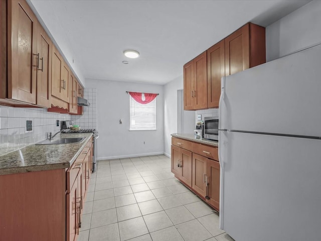 kitchen with light tile patterned floors, a sink, baseboards, decorative backsplash, and appliances with stainless steel finishes