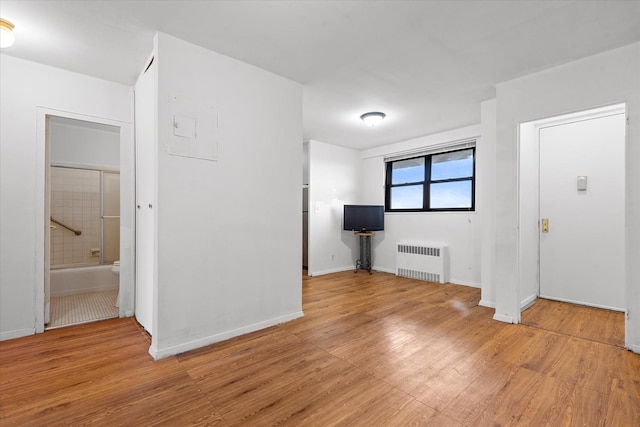 interior space with radiator heating unit, baseboards, and light wood-style flooring