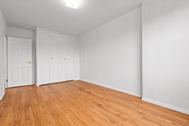 unfurnished bedroom with a closet, light wood finished floors, and baseboards
