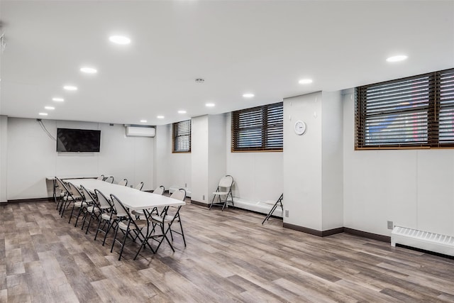dining room with baseboards, wood finished floors, a wall mounted AC, and recessed lighting