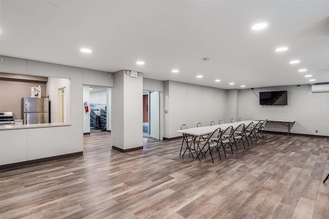 dining room featuring baseboards, wood finished floors, an AC wall unit, and recessed lighting
