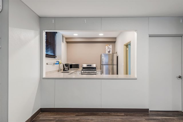 kitchen featuring recessed lighting, dark wood finished floors, light countertops, a sink, and appliances with stainless steel finishes