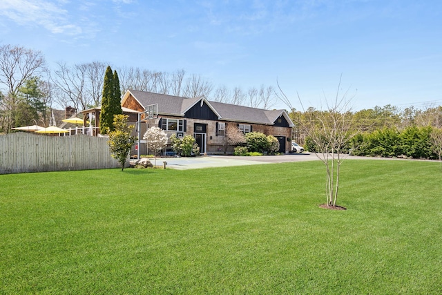 ranch-style home with roof with shingles, fence, and a front yard