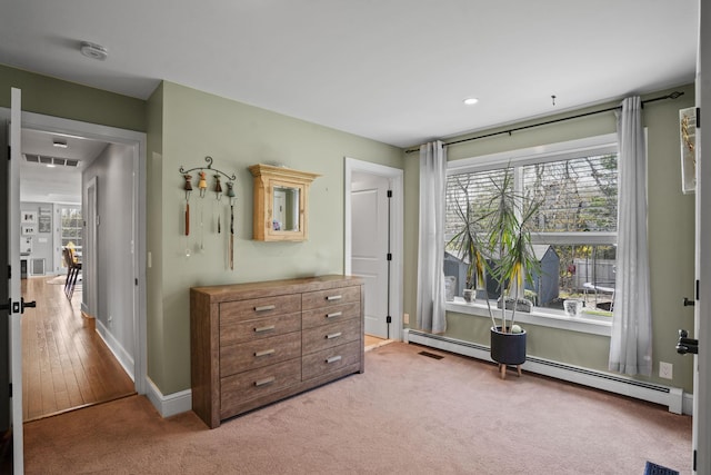 bedroom featuring light colored carpet, baseboards, a baseboard heating unit, and multiple windows
