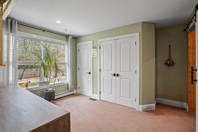office area with a barn door, carpet, baseboards, a baseboard radiator, and visible vents