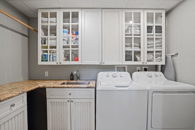 clothes washing area featuring a sink, cabinet space, and washer and dryer