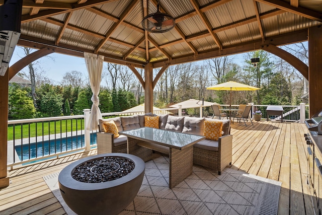 deck with a gazebo, outdoor dining area, an outdoor pool, and an outdoor fire pit