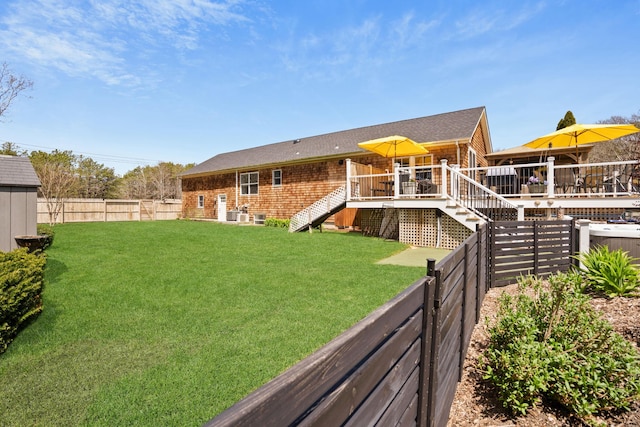 rear view of house featuring a yard, stairway, a wooden deck, and a fenced backyard
