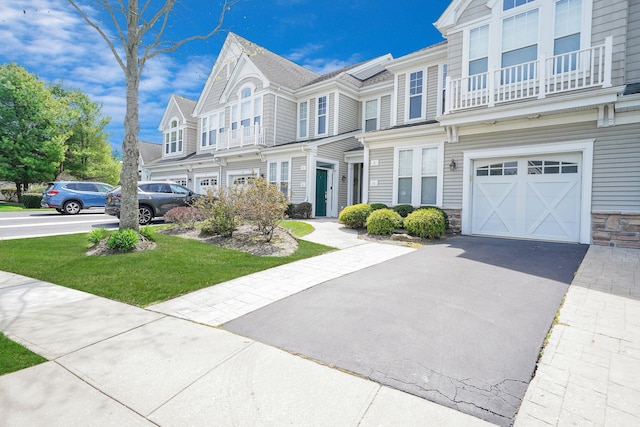 10 Symphony Dr, Lake Grove, NY 11755 - townhome / multi-family property featuring a garage, aphalt driveway, a balcony, and stone siding