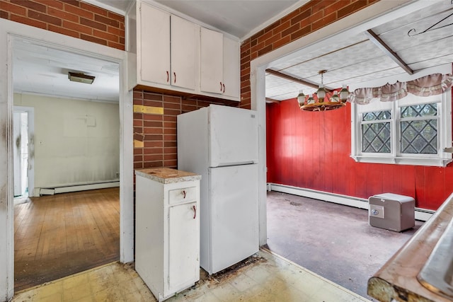 kitchen with baseboard heating, white cabinetry, light countertops, and freestanding refrigerator