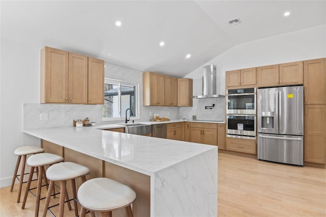 kitchen featuring visible vents, wall chimney exhaust hood, a sink, vaulted ceiling, and stainless steel appliances