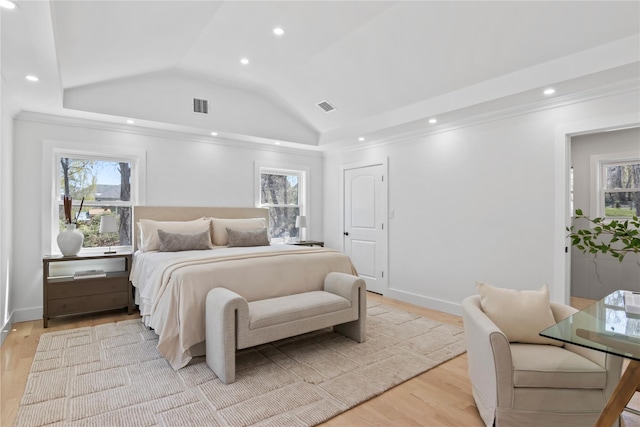 bedroom with visible vents, light wood finished floors, and lofted ceiling