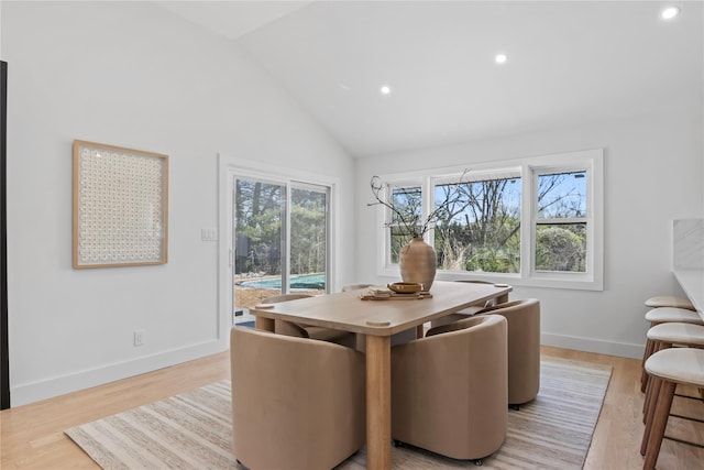 dining space with high vaulted ceiling, light wood finished floors, and recessed lighting