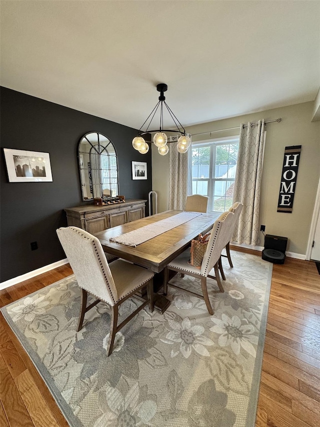 dining room with light wood-style floors, a wealth of natural light, baseboards, and an inviting chandelier