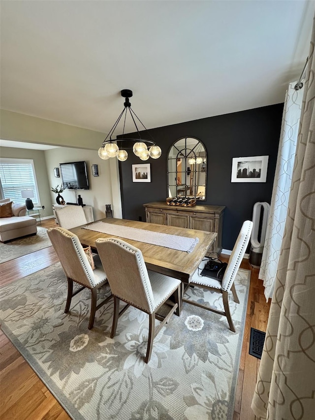 dining area with wood finished floors and an inviting chandelier