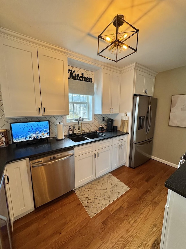 kitchen with white cabinets, a sink, dark wood-style flooring, backsplash, and appliances with stainless steel finishes