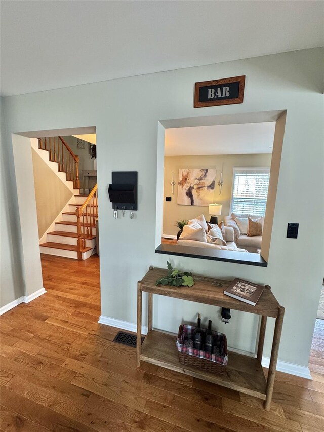 hallway with visible vents, baseboards, wood finished floors, and stairway