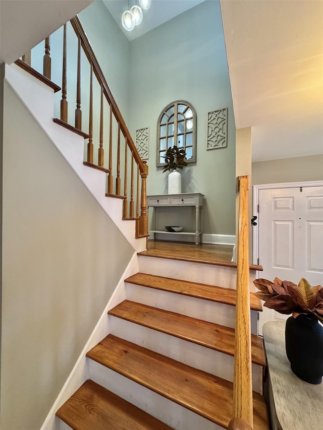 staircase featuring a chandelier, wood finished floors, and baseboards