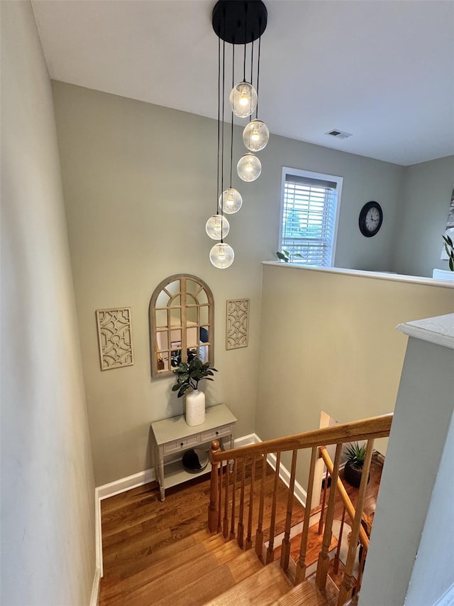 stairway featuring baseboards, wood finished floors, and visible vents