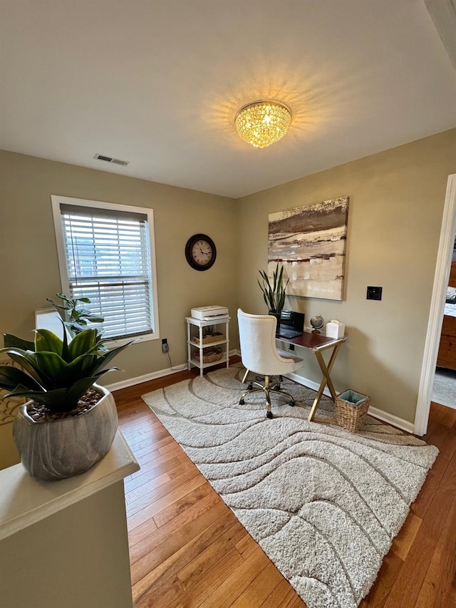 office space featuring hardwood / wood-style floors, baseboards, and visible vents