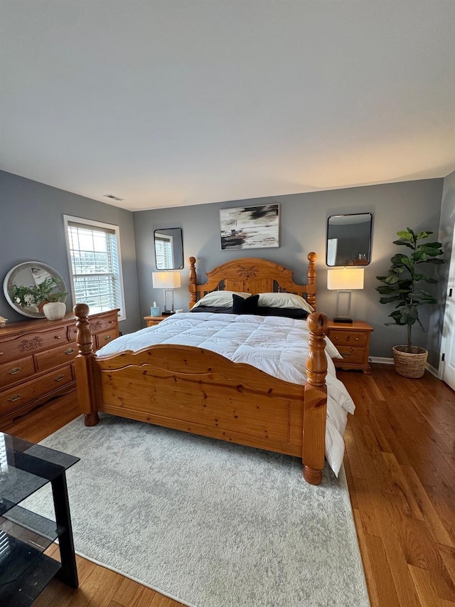bedroom featuring visible vents, baseboards, and wood finished floors