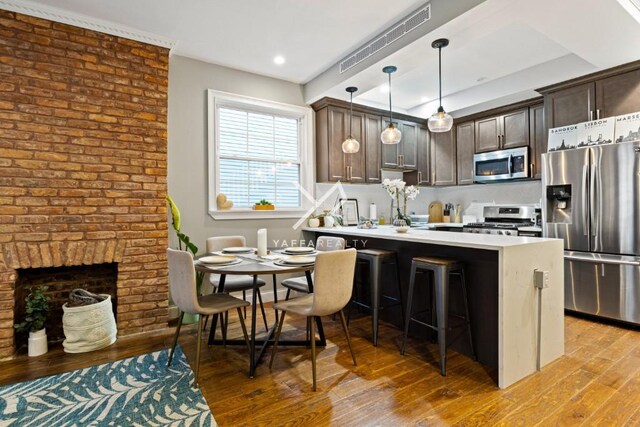 kitchen featuring light countertops, dark brown cabinets, visible vents, a peninsula, and appliances with stainless steel finishes