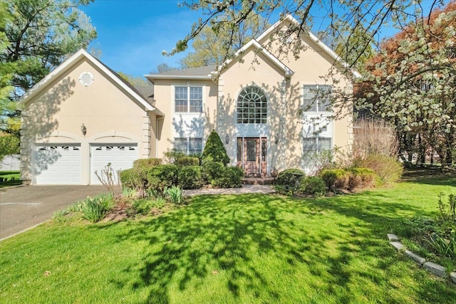 view of front facade with stucco siding, an attached garage, driveway, and a front yard