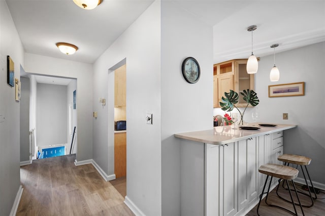 corridor with baseboards, wood finished floors, and an upstairs landing