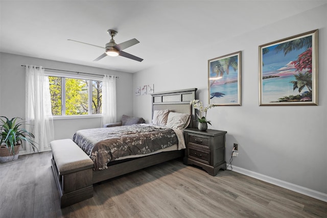 bedroom with a ceiling fan, wood finished floors, and baseboards