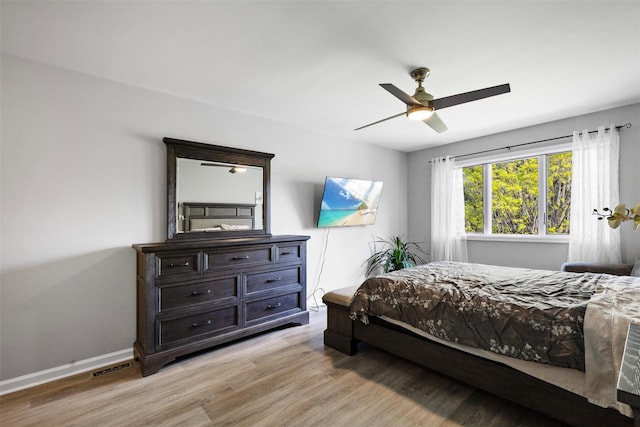 bedroom with baseboards, light wood-type flooring, visible vents, and a ceiling fan