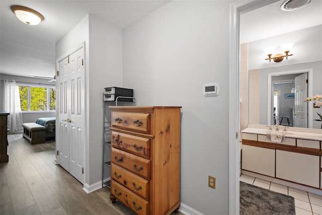 hallway featuring baseboards, light wood-type flooring, and a sink