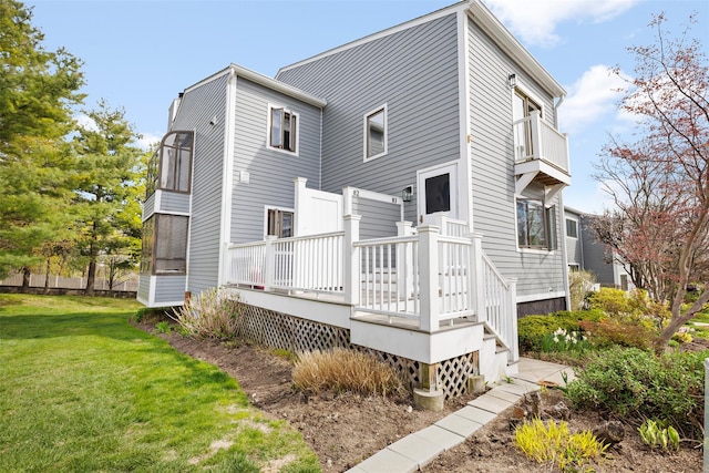 rear view of house with a deck, a balcony, and a yard