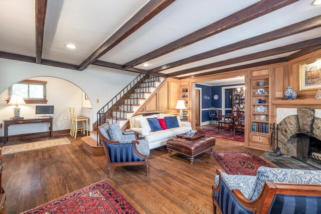 living area with arched walkways, baseboards, wood finished floors, stairs, and a fireplace
