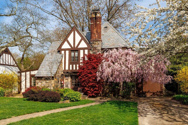 view of front of house with stone siding, a front lawn, and a chimney