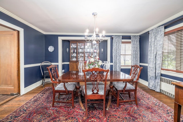dining space featuring baseboards, wood finished floors, an inviting chandelier, and crown molding