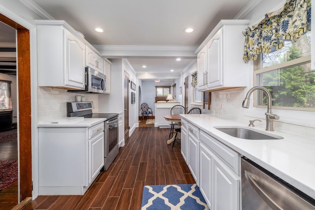 kitchen featuring white cabinets, crown molding, stainless steel appliances, and a sink