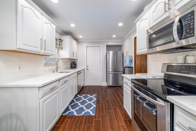 kitchen featuring white cabinets, dark wood-style floors, ornamental molding, a sink, and appliances with stainless steel finishes
