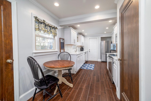 kitchen with white cabinets, stainless steel appliances, a sink, baseboards, and light countertops